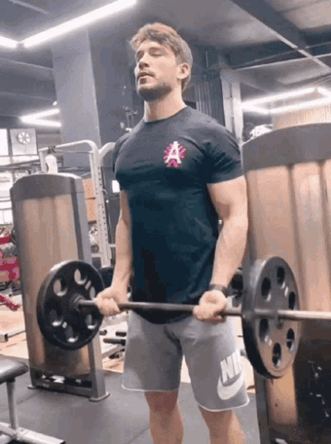 a man in a black shirt with the letter a on it is lifting a barbell