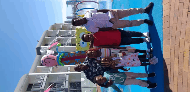 a group of people posing for a picture in front of a spongebob sculpture