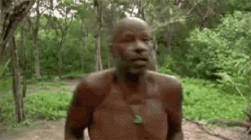 a shirtless man is walking through a forest .