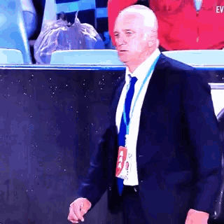 a man in a suit and tie with a lanyard around his neck with the word ev on it