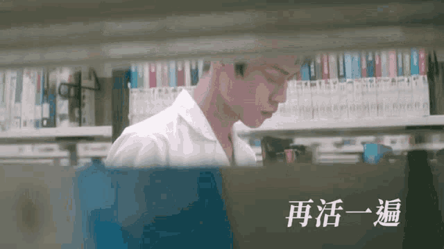 a man is standing in front of a bookshelf in a library .