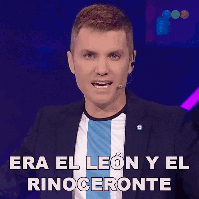 a man speaking into a microphone with the words era el leon y el rinoceronte behind him