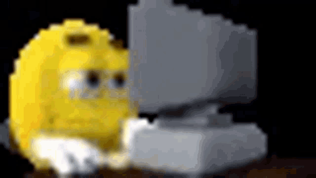 a yellow smiley face is sitting at a desk in front of a computer .