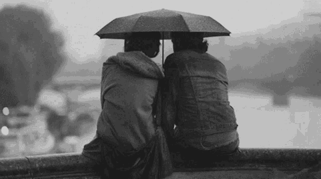 two people are sitting under an umbrella on a bridge