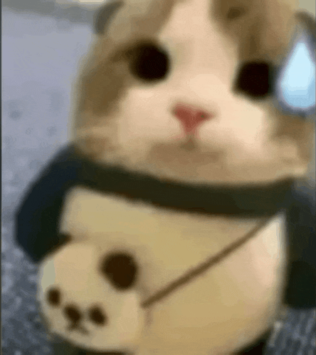 a stuffed cat is wearing a panda costume and a scarf .
