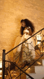 a woman in a long white dress is walking down stairs