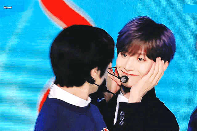 a man with purple hair is touching the face of another man