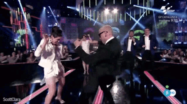 a man and a woman are dancing on a stage with the words scottclara on the bottom right
