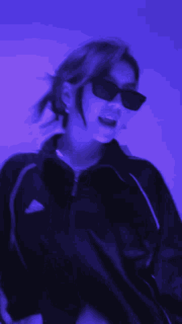 a woman wearing sunglasses and an adidas jacket