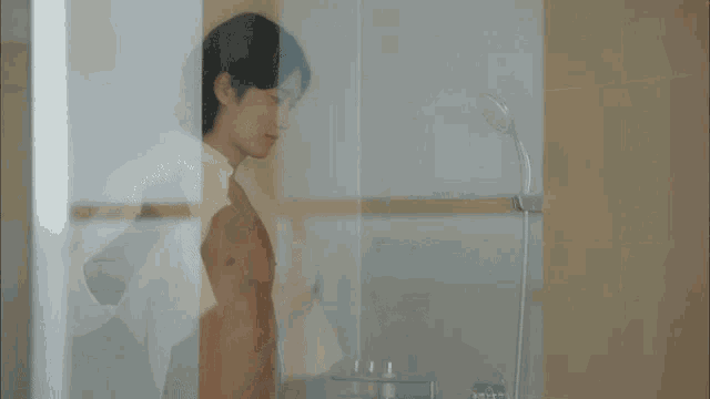 a shirtless man is taking a shower in the bathroom