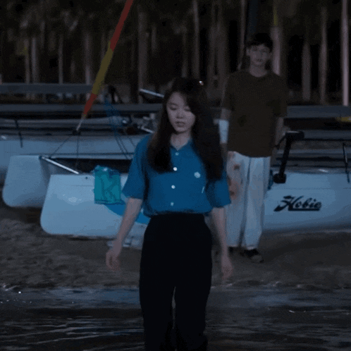 a man and a woman standing in front of a boat that says kolie on it