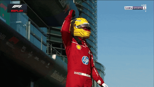 a man wearing a yellow hp helmet stands in front of a skyscraper