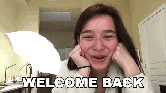 a woman is smiling with the words welcome back on her face