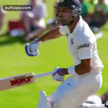 a cricket player is swinging a bat while wearing a helmet on a field .