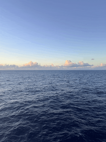 a large body of water with a blue sky and clouds