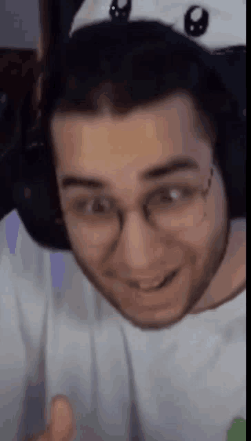 a close up of a man wearing headphones and glasses making a funny face .