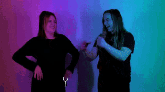 two women are standing next to each other and one of them is pointing at the other 's waist .