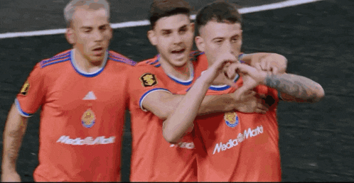 a group of soccer players wearing red jerseys with media markt written on them