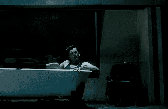 a man in a bathtub smoking a cigarette in the dark
