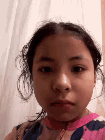 a little girl 's face is shown upside down with a white curtain behind her