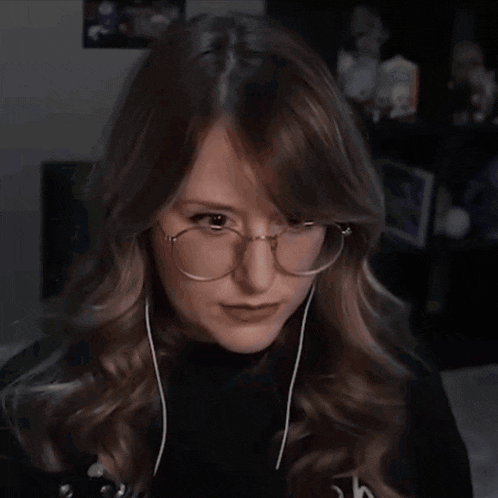 a woman wearing headphones and a black shirt is making a funny face with her hands in the air .