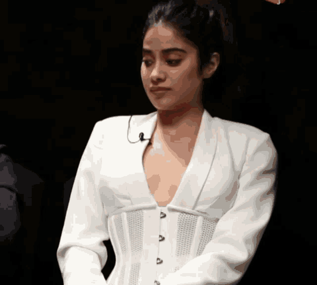 a woman wearing a white corset and a white jacket is looking down
