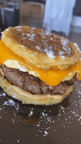 a close up of a hamburger with cheese and eggs on a pancake