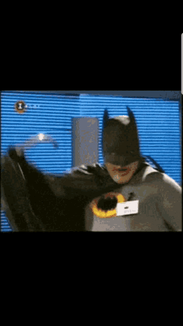 a man in a batman costume is standing in front of a tv screen