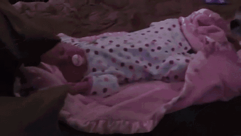 a person is laying on a bed with a pink blanket on .