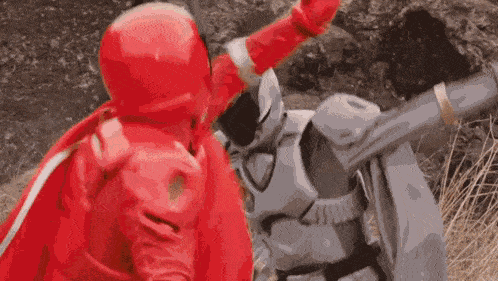 a red ninja is fighting a silver ninja in a field .