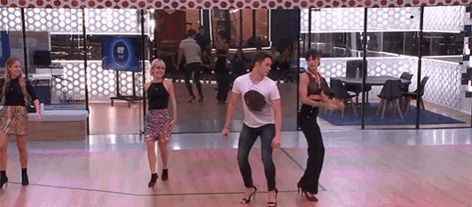 a group of people are dancing on a dance floor in front of a sign that says tv .