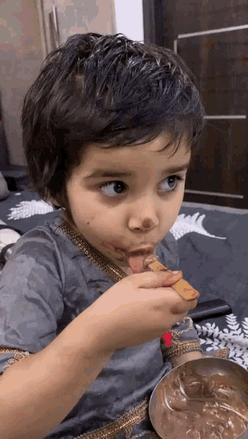 a little boy is eating a cookie with chocolate sauce on his face
