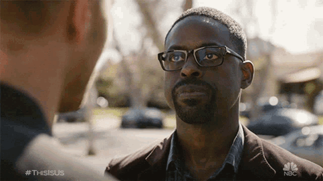 a man wearing glasses is talking to another man in a nbc advertisement