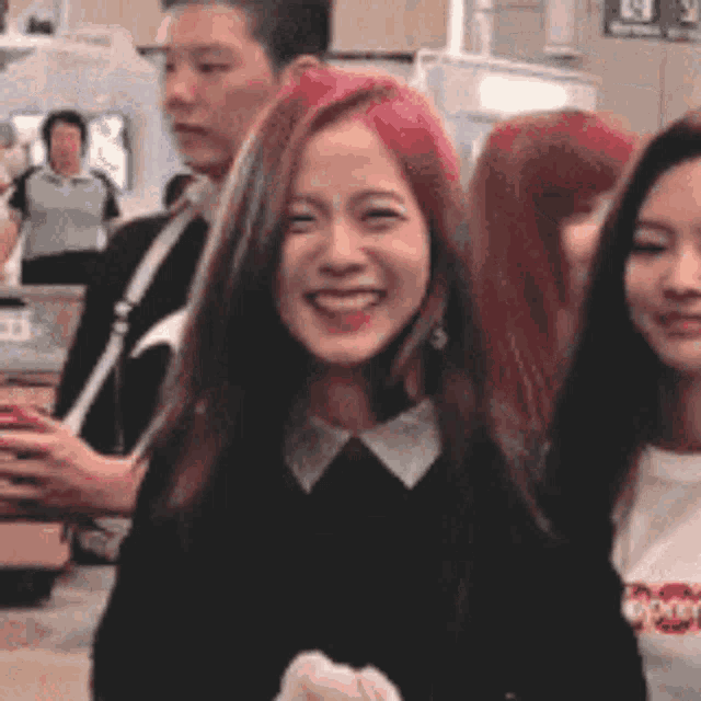 a woman with red hair is smiling while standing next to a group of people .