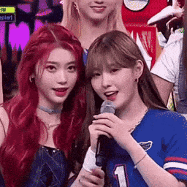 two girls are standing next to each other holding microphones .