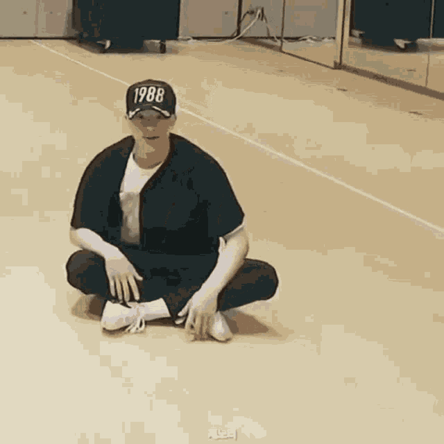 a man is sitting on the floor wearing a 1988 hat