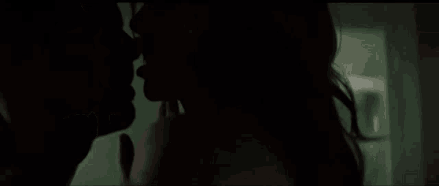 a man and a woman are kissing in the dark in a room .