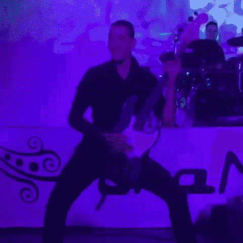 a man is playing a guitar in front of a purple wall with the letter a on it