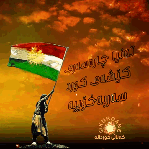 a man holding a kurdish flag in front of an orange sky