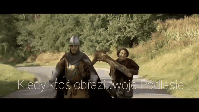 a man in a knight 's armor is walking down a road with another man