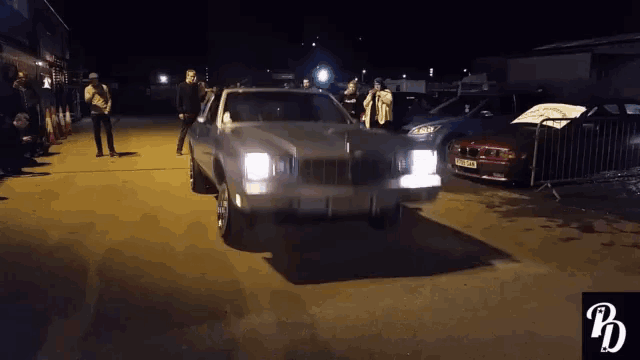 a white car is parked in a parking lot with people watching
