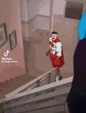 a man in a red cape is walking down stairs .