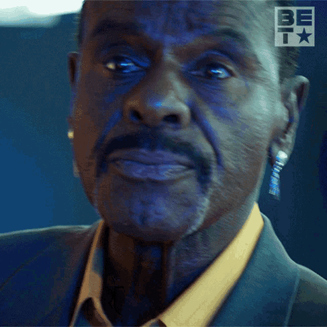 a close up of a man 's face with a be t logo in the background