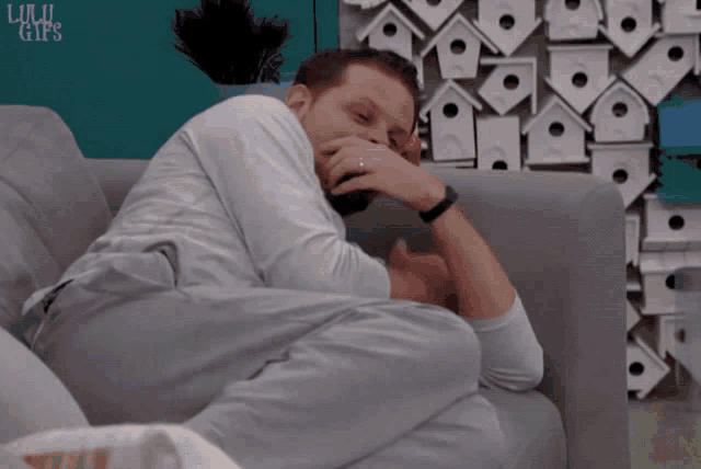 a man sits on a couch in front of a wall with birdhouses and the words lulu gifs written on it