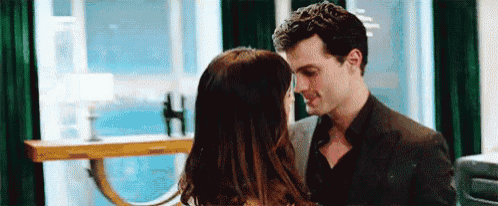 a man and a woman are standing next to each other in a room and kissing .