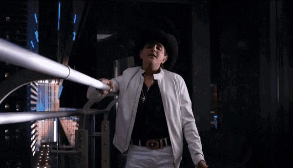 a man in a cowboy hat is holding a light saber in his hand .