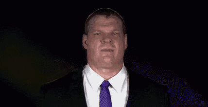 a man in a suit and tie is making a funny face in the dark .