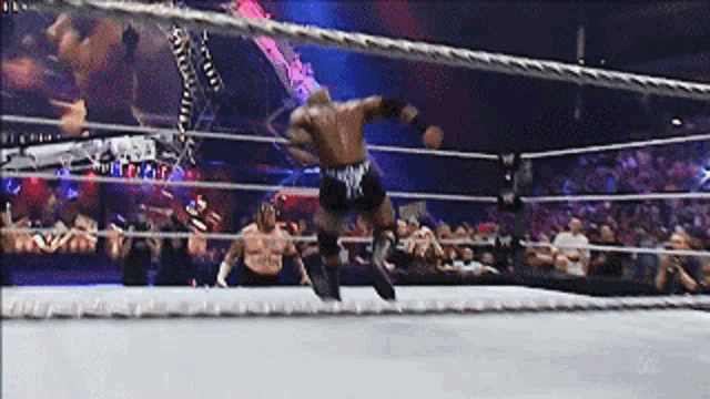 a wrestler is jumping over the ropes in a ring