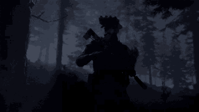 a man holding a gun in a dark forest with trees in the background