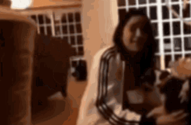 a blurry picture of a woman sitting in a chair in front of a window .